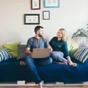A couple on the sofa checking figures on a laptop