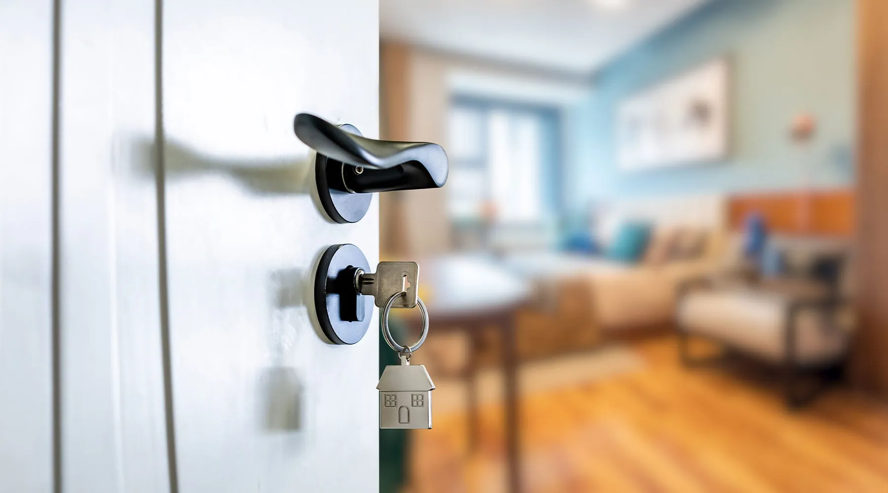Keys in the lock of a front door with a bright new home behind
