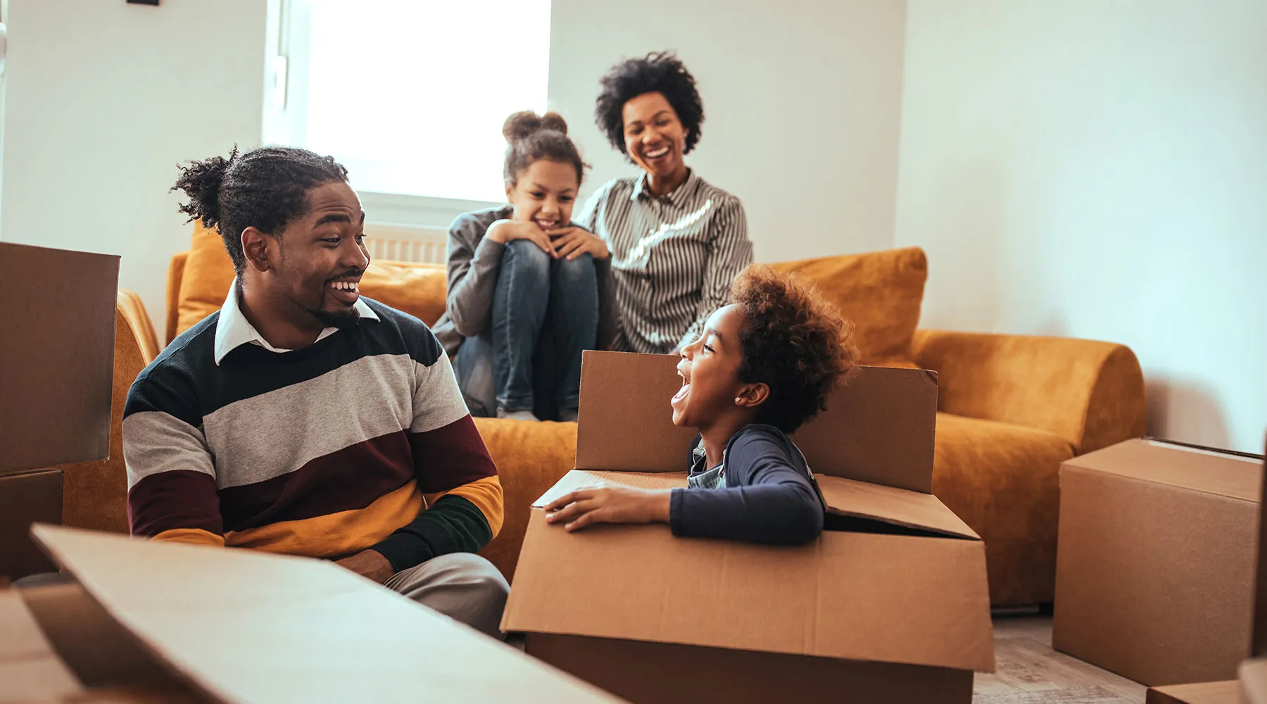 A family with young children playing among moving boxes